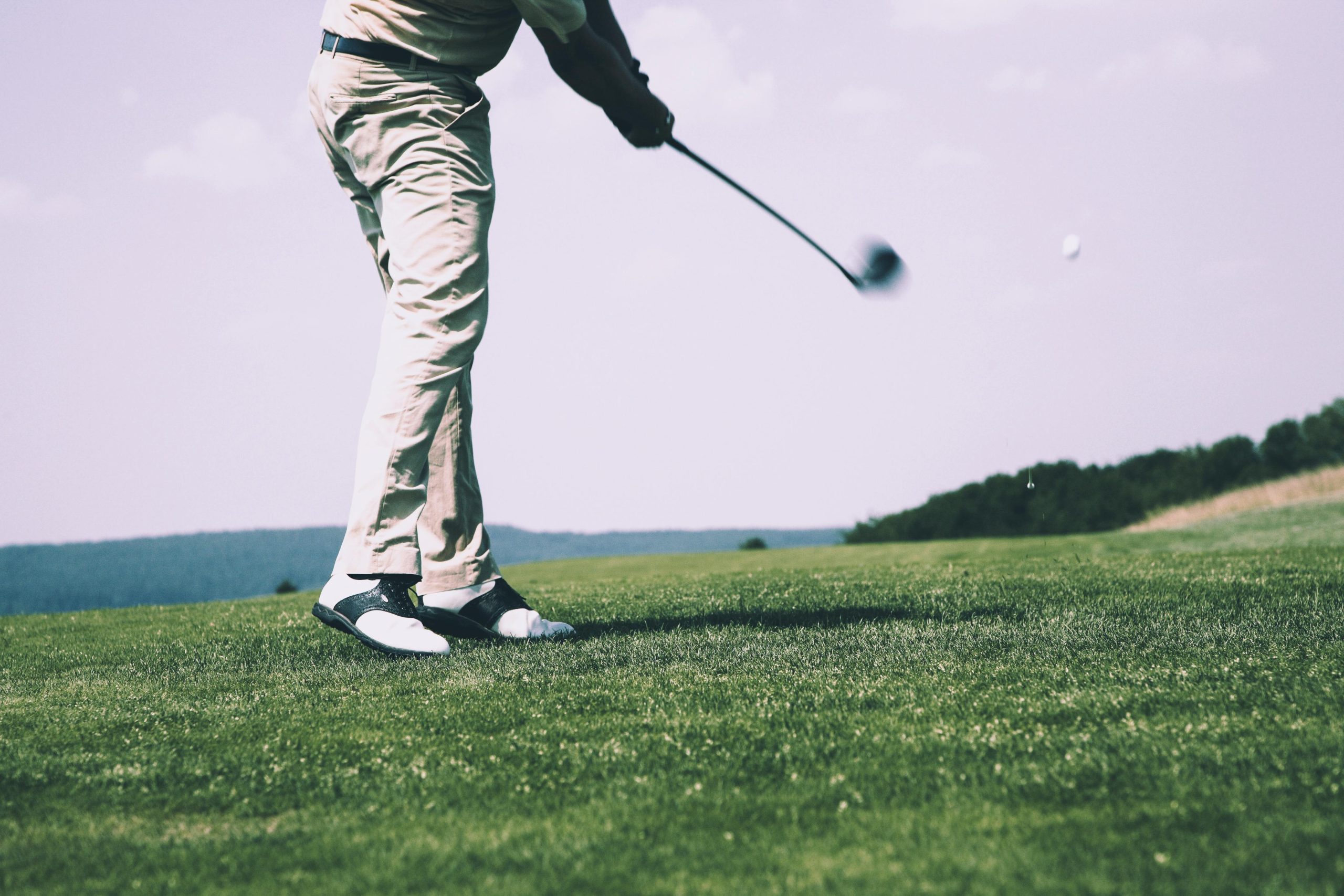 Golfer mid-swing on a scenic golf course in Sri Lanka under clear skies Play Golf in Sri Lanka
