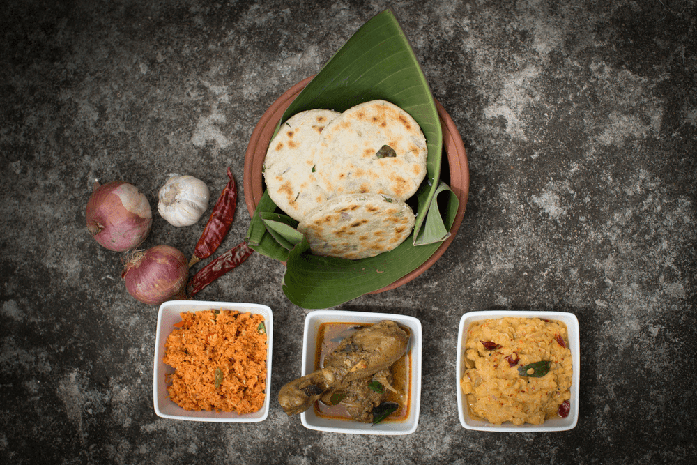 Traditional Sri Lankan food tour experience with roti, chicken curry, and sambol served on banana leaf with onions and spices