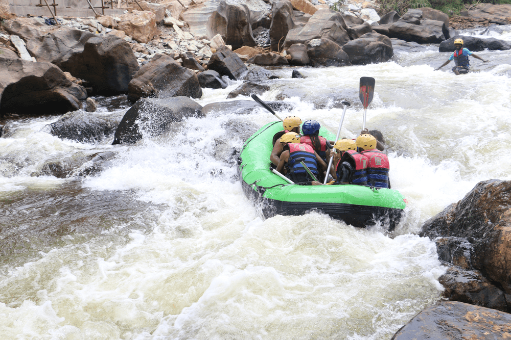 Adventurers enjoying Kithulgala water rafting on the Kelani River in Sri Lanka, navigating white-water rapids in a green inflatable raft 