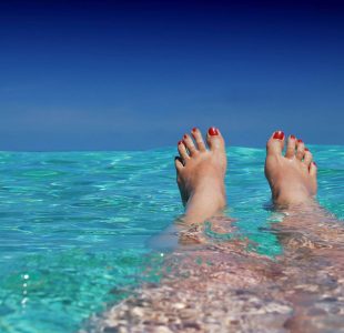 Relaxed feet in calm turquoise water by distant horizon. Discover Islandwyde’s tranquil sri lanka holiday packages journeys